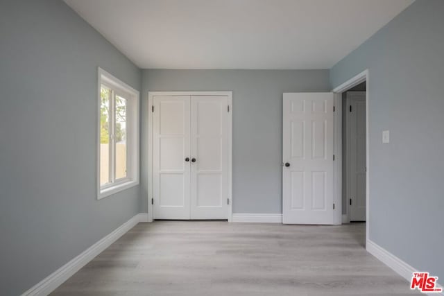 unfurnished bedroom with a closet and light wood-type flooring