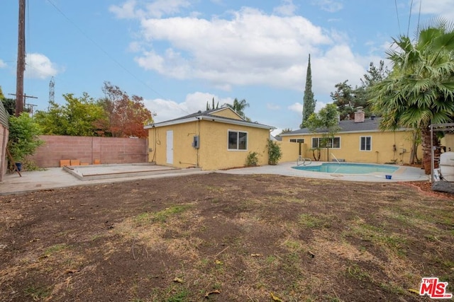 back of house with a fenced in pool and a patio