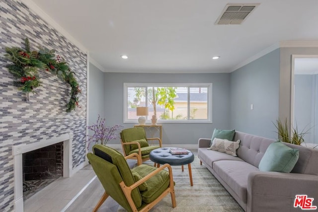 living room with a tiled fireplace, crown molding, and light wood-type flooring