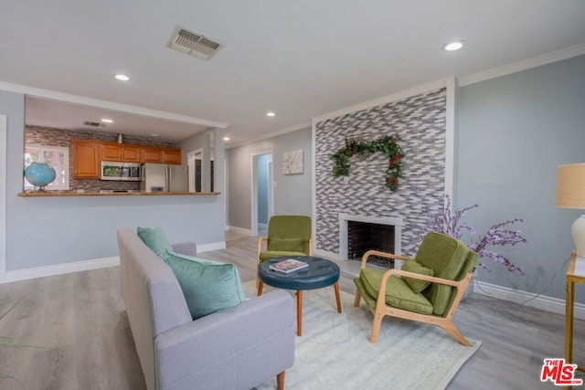 living room with a fireplace, ornamental molding, and light wood-type flooring