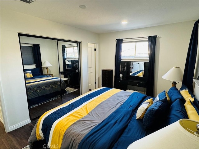 bedroom with dark hardwood / wood-style floors and a closet