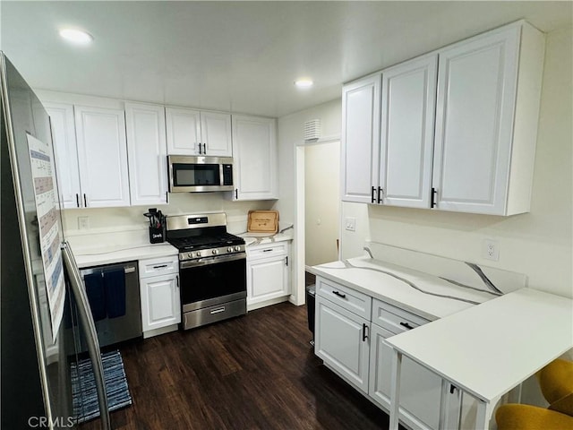 kitchen with white cabinets, appliances with stainless steel finishes, dark hardwood / wood-style flooring, and a breakfast bar