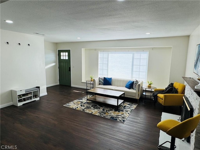 living room featuring a textured ceiling, a fireplace, and dark wood-type flooring