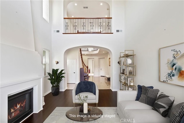 living room featuring a towering ceiling and dark hardwood / wood-style flooring