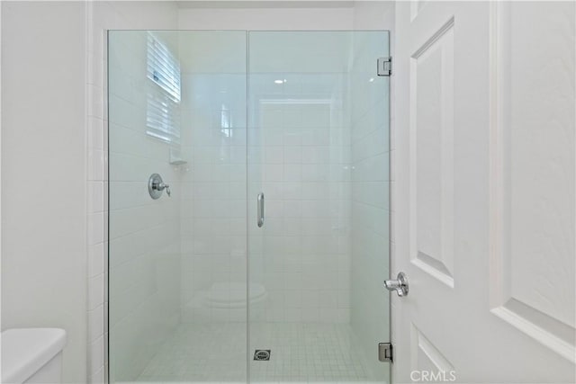 bathroom with a shower with door and toilet