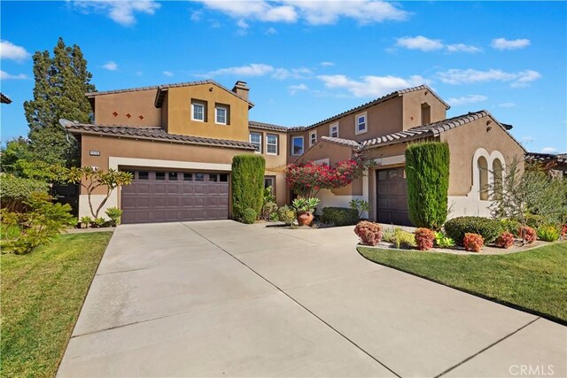 mediterranean / spanish home featuring a garage and a front yard