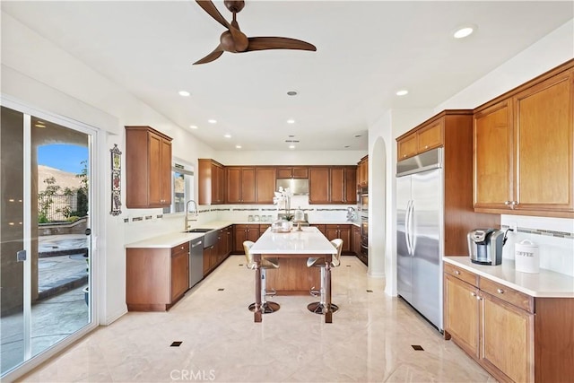 kitchen featuring a kitchen island, appliances with stainless steel finishes, sink, a kitchen bar, and ceiling fan