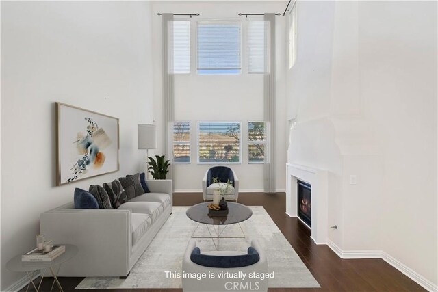 living room with dark wood-type flooring and a towering ceiling