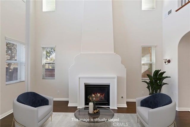 sitting room with a high ceiling and wood-type flooring