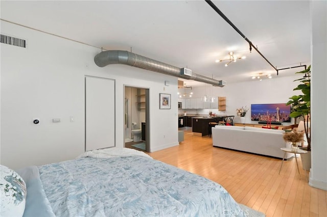 bedroom featuring ensuite bath and light hardwood / wood-style floors