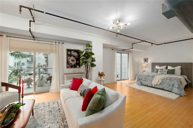 bedroom with an inviting chandelier, light hardwood / wood-style flooring, and access to exterior