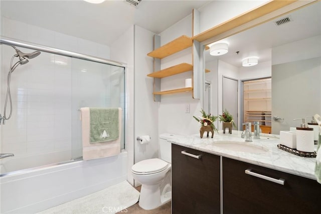 full bathroom featuring toilet, bath / shower combo with glass door, and vanity