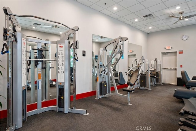 exercise room featuring a high ceiling, a drop ceiling, and ceiling fan