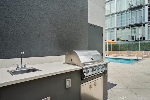 view of patio with an outdoor kitchen, grilling area, sink, and a community pool