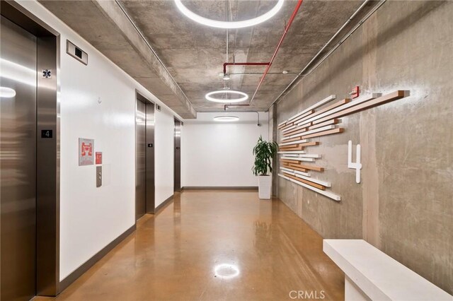 corridor featuring elevator and concrete floors