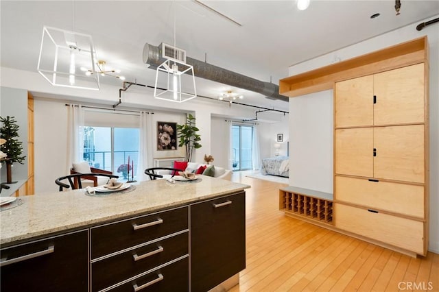 kitchen featuring light stone countertops, light wood-type flooring, and dark brown cabinetry