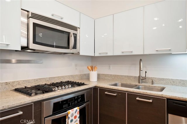 kitchen featuring appliances with stainless steel finishes, white cabinets, sink, and dark brown cabinetry