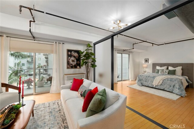 bedroom featuring light hardwood / wood-style floors, a notable chandelier, access to outside, and multiple windows