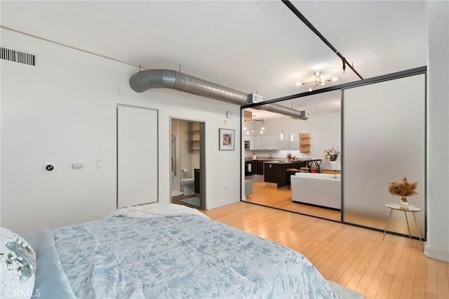 bedroom featuring ensuite bathroom, light hardwood / wood-style floors, and a closet