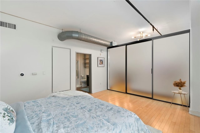 bedroom with ensuite bath and light hardwood / wood-style flooring