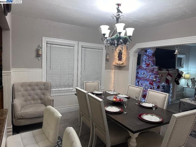 dining area featuring carpet, a textured ceiling, and a notable chandelier