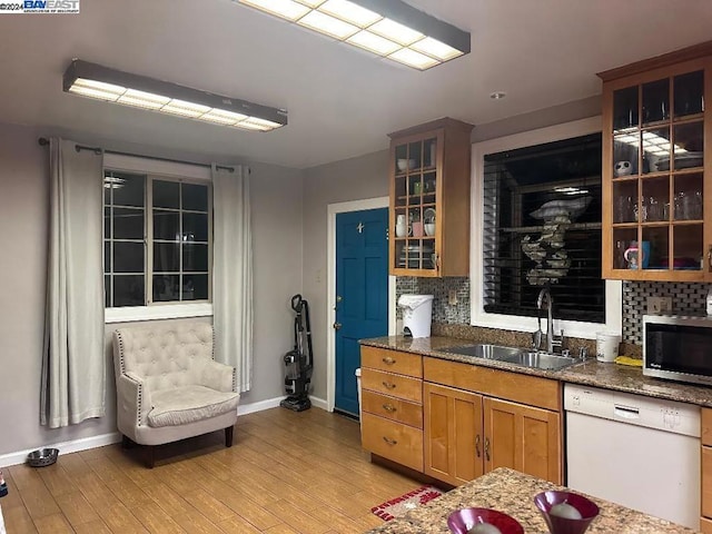 kitchen featuring dishwasher, sink, backsplash, dark stone countertops, and light hardwood / wood-style floors