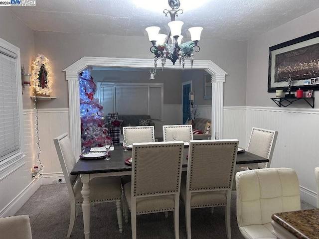 dining area featuring carpet floors, a textured ceiling, and a notable chandelier