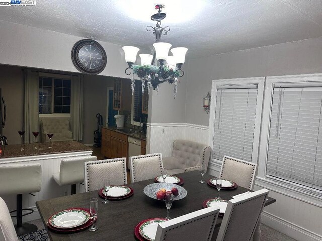 dining area with sink, a textured ceiling, and an inviting chandelier