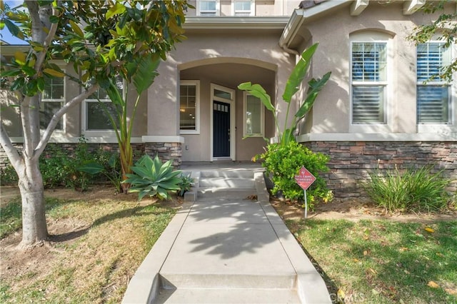 11465 Oakford Ln, Porter Ranch, CA 91326 - view of exterior entry featuring stucco siding, stone siding, and a porch
