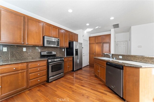 11465 Oakford Ln, Porter Ranch, CA 91326 - kitchen with appliances with stainless steel finishes, wood finished floors, brown cabinetry, and recessed lighting