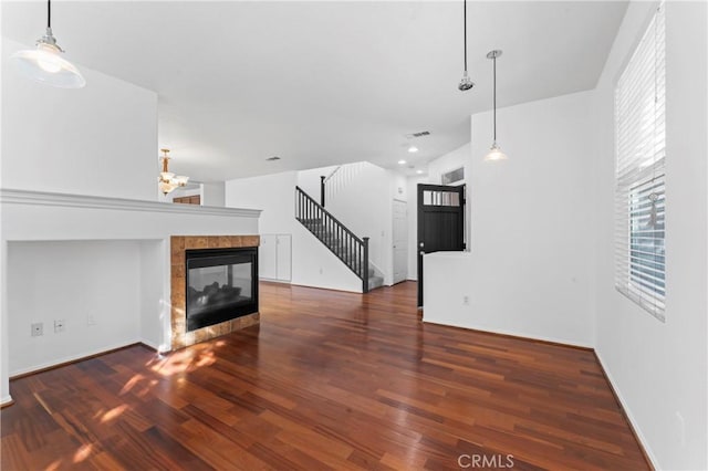 unfurnished living room with dark hardwood / wood-style flooring, plenty of natural light, and a tiled fireplace