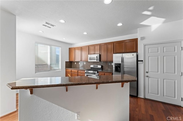 11465 Oakford Ln, Porter Ranch, CA 91326 - kitchen featuring stainless steel appliances, a kitchen breakfast bar, dark wood finished floors, backsplash, and recessed lighting