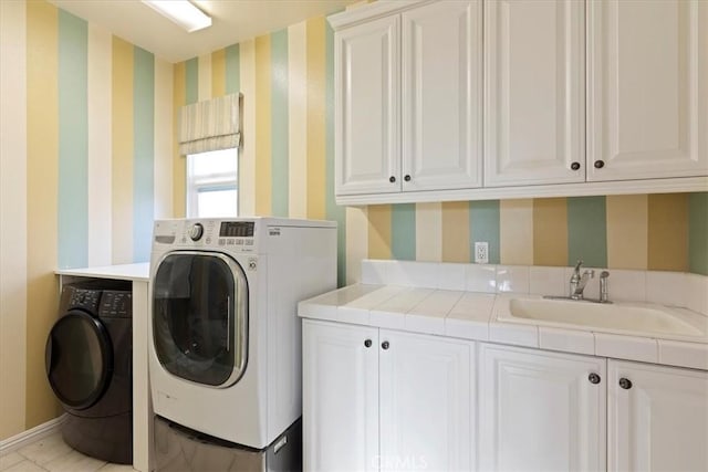 laundry area featuring cabinets, light tile patterned floors, washer and dryer, and sink