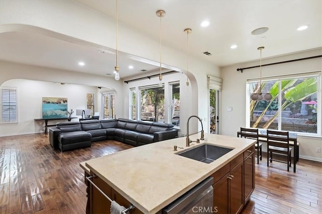 kitchen featuring sink, dishwasher, dark hardwood / wood-style floors, pendant lighting, and a kitchen island with sink