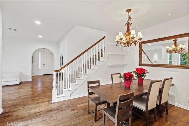 dining area with hardwood / wood-style floors and an inviting chandelier