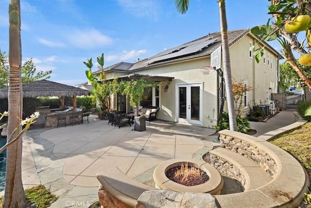 rear view of house featuring a fire pit, french doors, an outdoor bar, area for grilling, and a patio