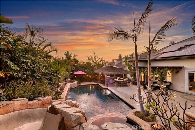 pool at dusk with a gazebo, pool water feature, and a patio area