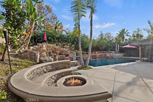 view of swimming pool featuring pool water feature, a patio, and a fire pit