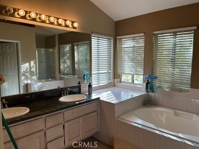 bathroom with separate shower and tub, vanity, and vaulted ceiling