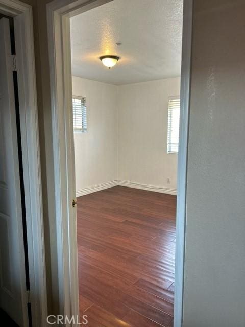 unfurnished room with a textured ceiling and dark hardwood / wood-style floors