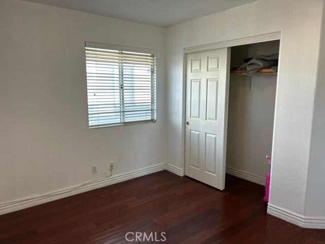 unfurnished bedroom with dark wood-type flooring and a closet