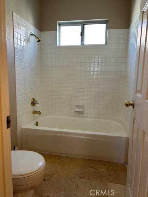 bathroom with tile patterned flooring, tiled shower / bath combo, and toilet