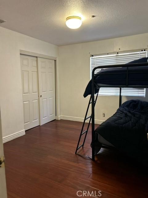 bedroom with a textured ceiling, a closet, and dark hardwood / wood-style floors