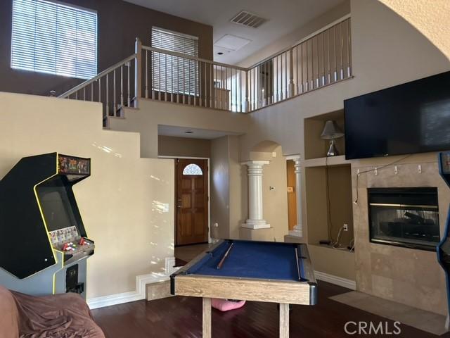 recreation room with a tile fireplace, a towering ceiling, dark hardwood / wood-style floors, and billiards