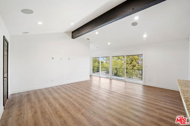 unfurnished living room featuring vaulted ceiling with beams and light hardwood / wood-style floors