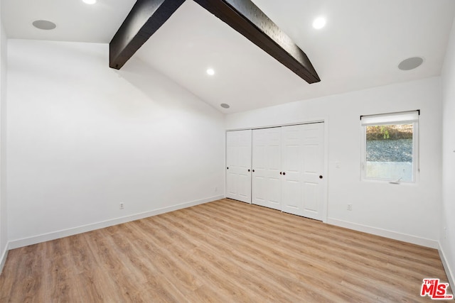 unfurnished bedroom featuring vaulted ceiling with beams and light wood-type flooring