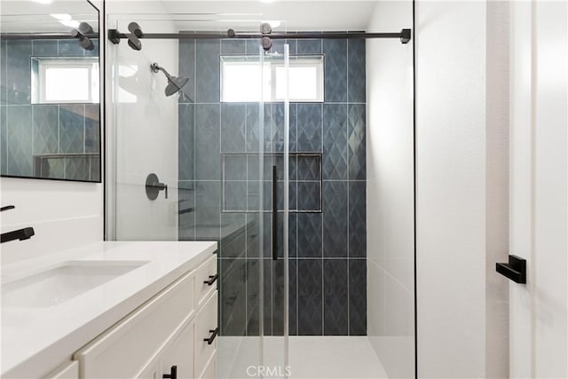 bathroom with a shower with door, vanity, and a healthy amount of sunlight