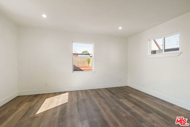 empty room with a healthy amount of sunlight and dark hardwood / wood-style flooring