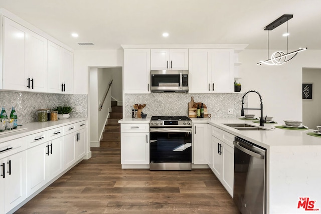 kitchen with pendant lighting, appliances with stainless steel finishes, sink, and white cabinets