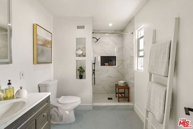 bathroom with vanity, tile patterned floors, toilet, and tiled shower